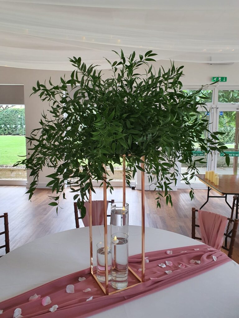 Ruscus foliage centrepiece on tall gold stand with 3 x floating candle vases & chiffon runner