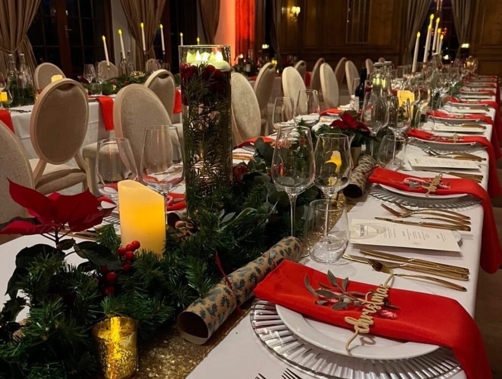 christmas tablescape of long garland, various candles & poinsettia