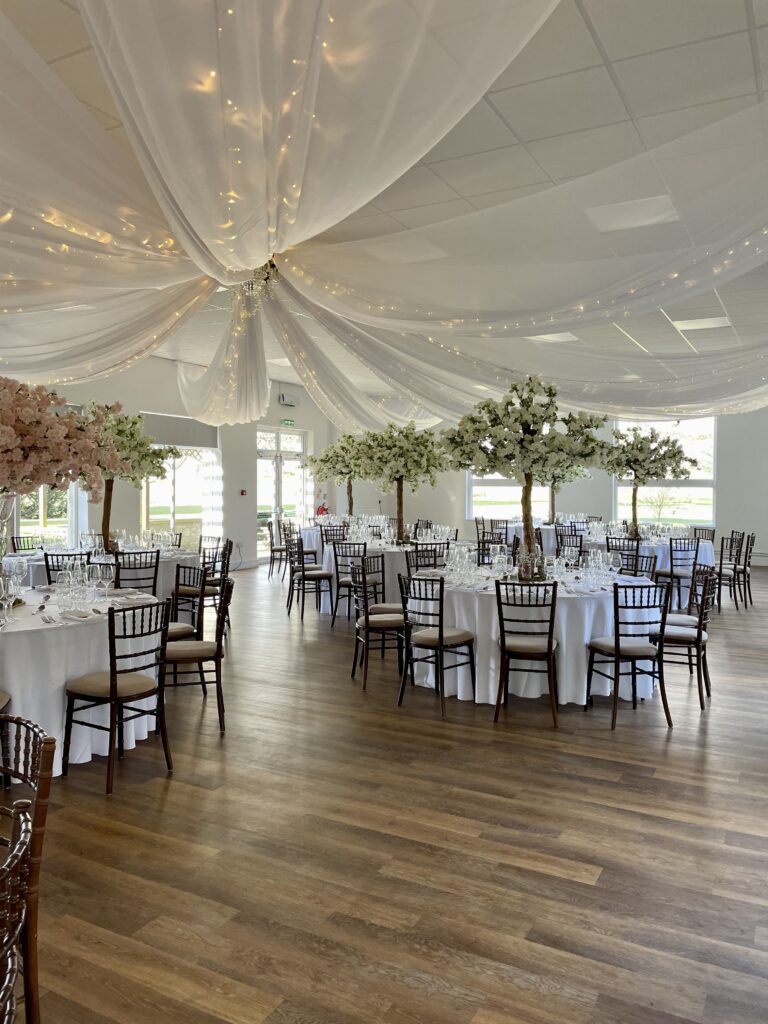 12 arms of white voile ceiling draping with warm white lights with ivory & pink 5ft blossom trees in the garden suite at Shuttleworth